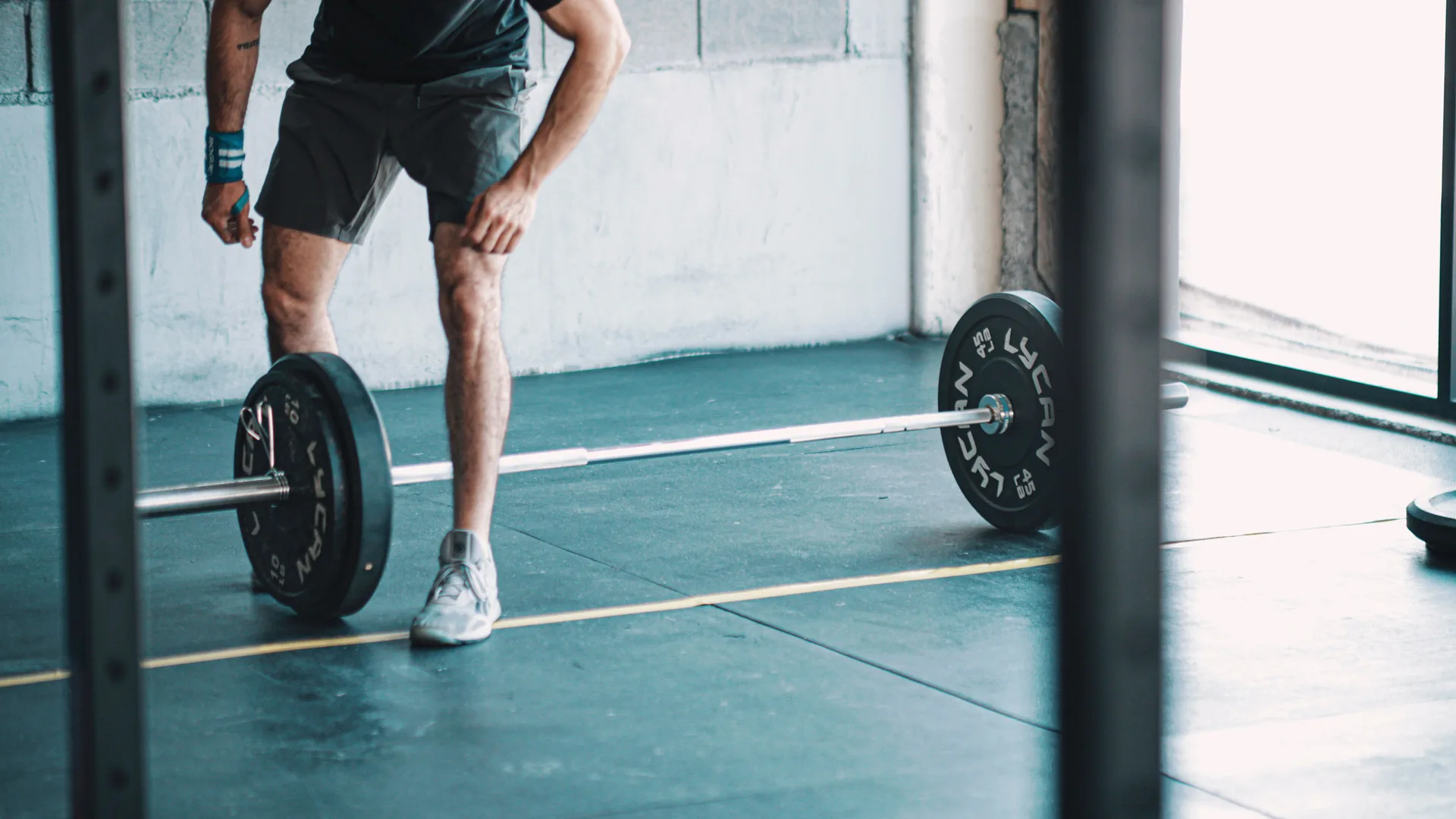 Athlete standing over a loaded barbell in a gym, preparing for strength training that supports HYROX performance